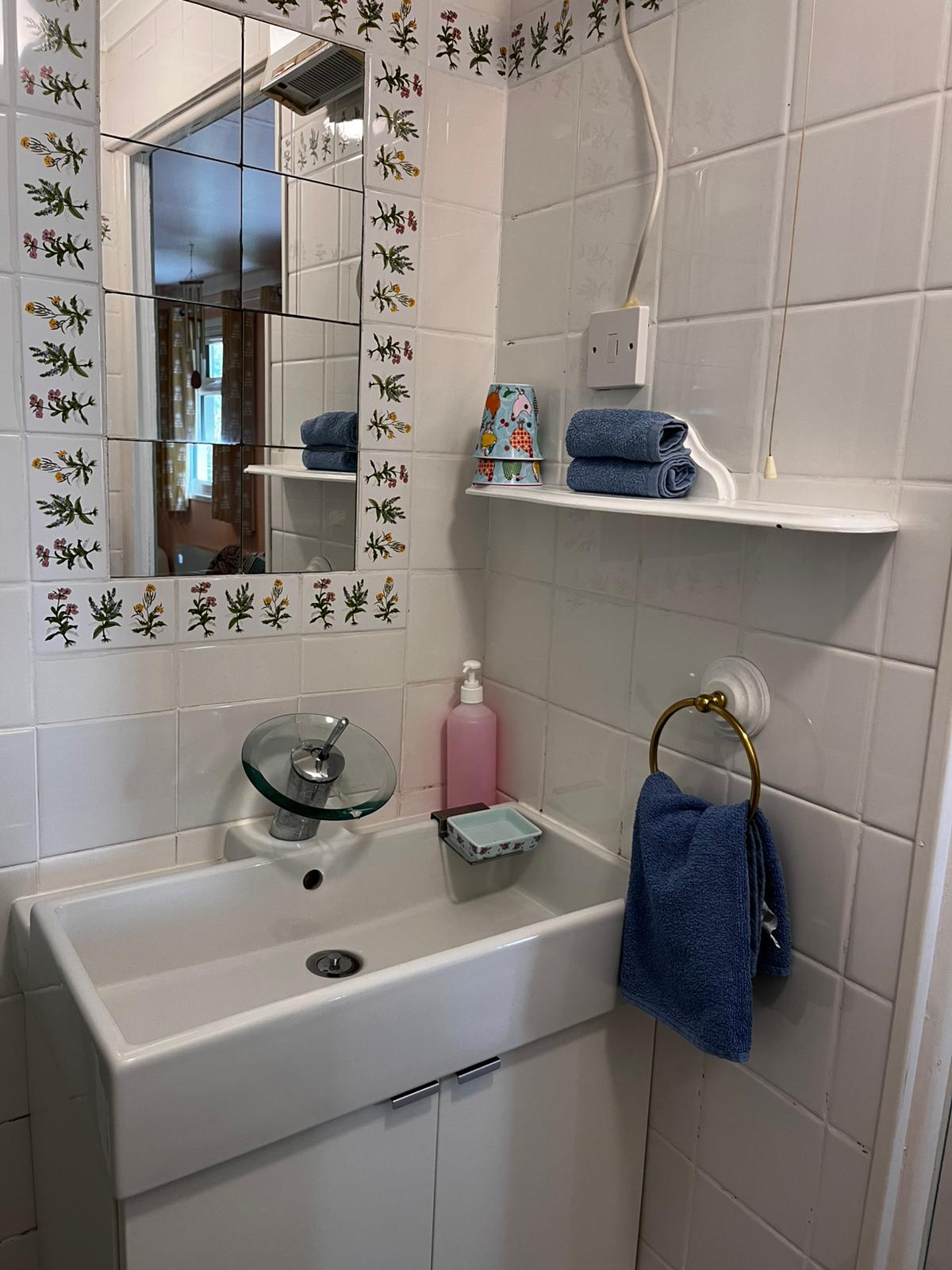 The cottage shower room with white tiles and botanical details